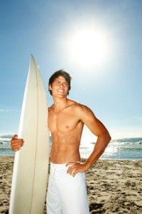 Man with a surfboard gets a portrait taken on the beach.