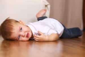 Little kid gets a picture taken of him by a portrait photographer while playing on the ground.