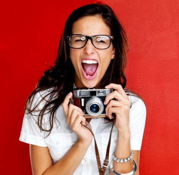 Photographer holding a camera on a red background.