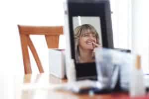 Candid portrait photo of a woman looking into a mirror