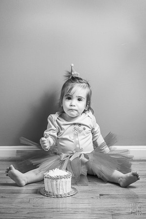 This photo was taken in a small hallway in order to use simplicity of the wood floor and the bare wall. Since the space itself is blank, we can focus on the little girl and her cake.